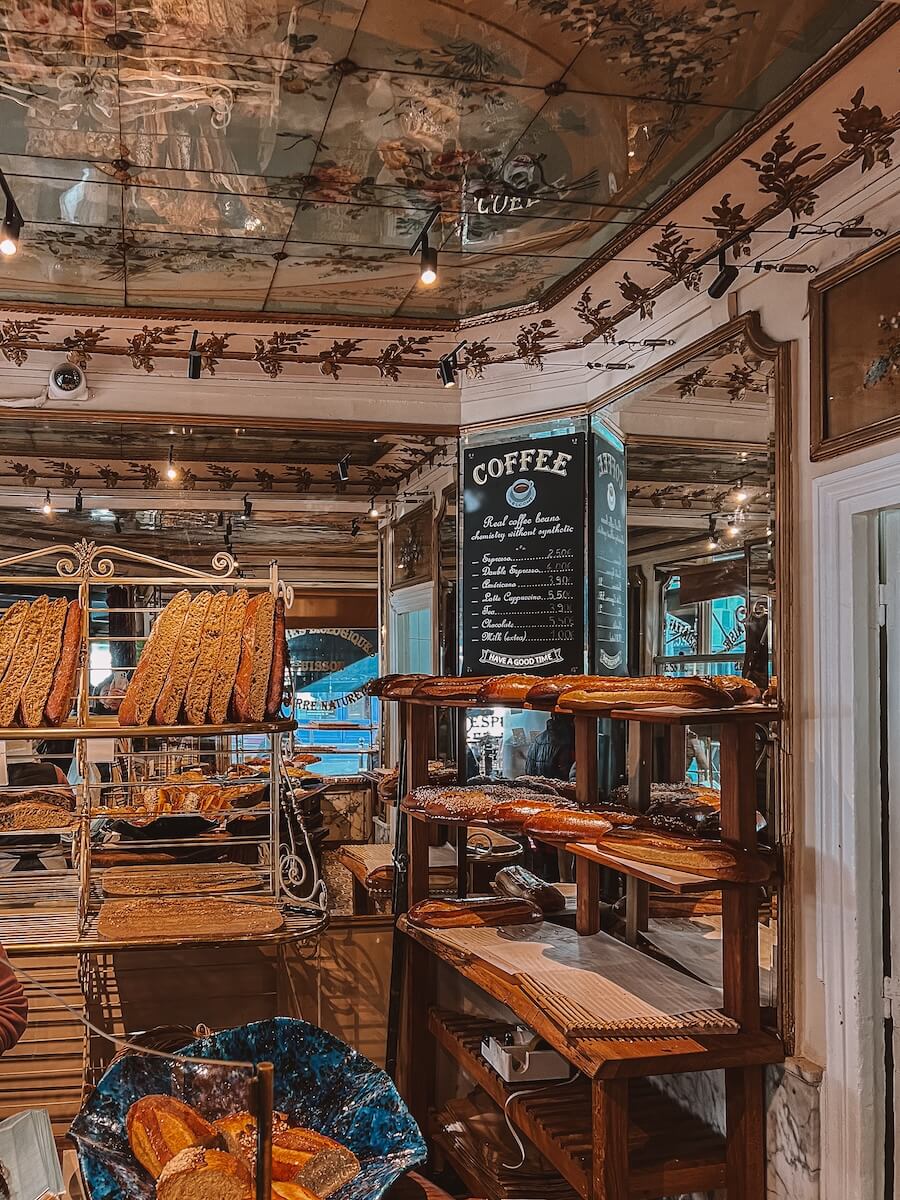 The inside of the famous Parisian bakery Du Pain et des Idees with fresh bread and croissants on the shelves - as seen in The Summer I Turned Pretty Paris scenes
