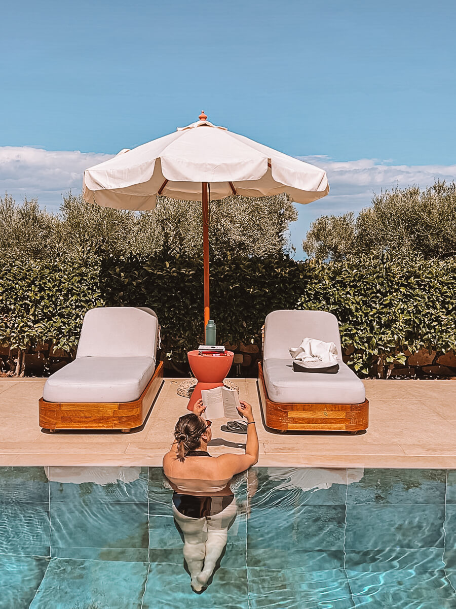 Girl reading in beautiful azure blue pool on reading retrat in Greece with Aweventurer 