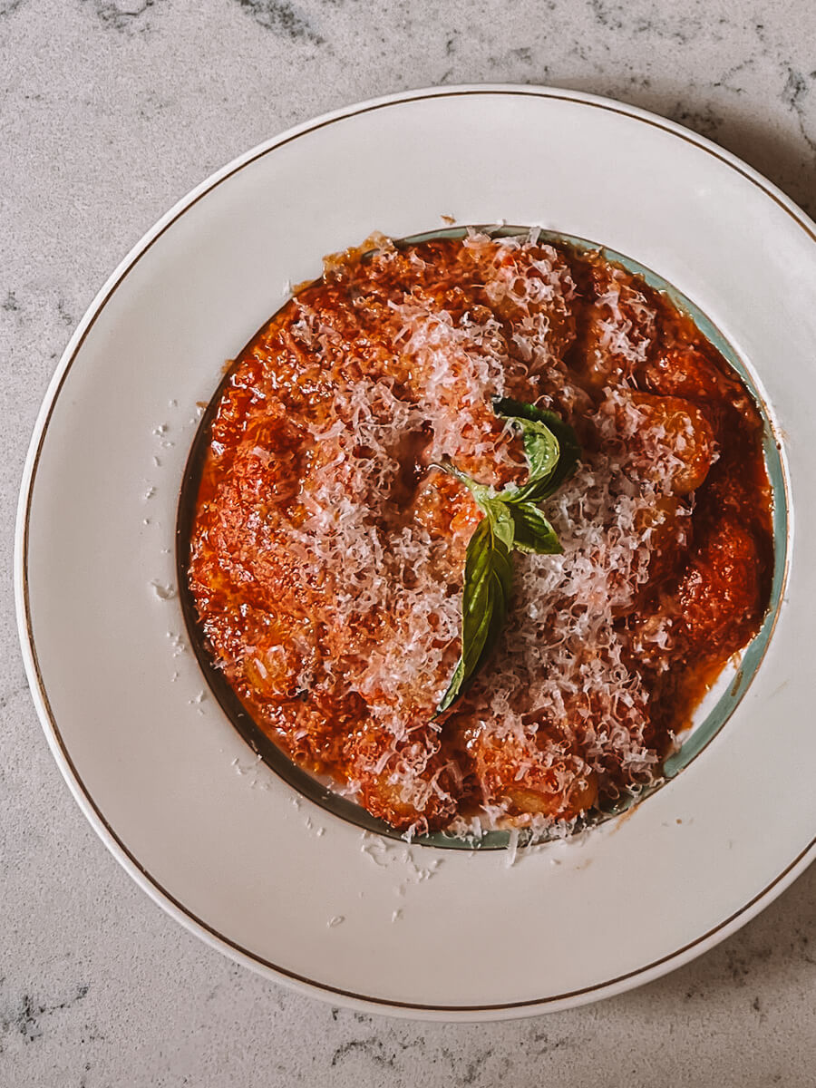 Close up of a plate of gnocchi covered in tomato sauce and parmesan cheese at Sullaluna in New York.
